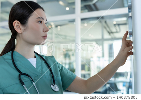 Dark-haired female doctor in lab coat setting the temperature range in a room Dark-haired female doctor in lab coat setting the temperature range in a room 140879803