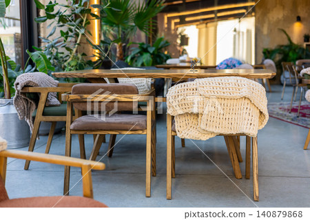 Wooden dining table with knitted blankets on chairs Wooden dining table with knitted blankets on chairs 140879868