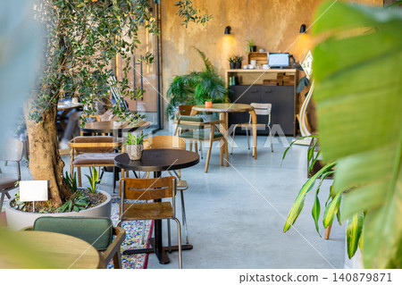 Small round table with plant near large olive tree 140879871