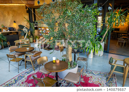 Large olive tree in pot standing among cafe tables Large olive tree in pot standing among cafe tables 140879887
