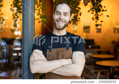 Happy bearded man wearing apron standing with crossed arms Happy bearded man wearing apron standing with crossed arms 140880050