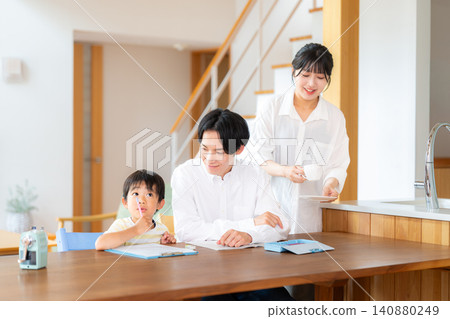 一個一年級男孩在學習，他的父母在教他。 140880249