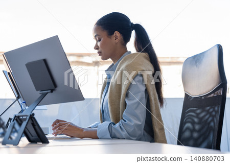 Focused young woman typing on keyboard in office Focused young woman typing on keyboard in office 140880703