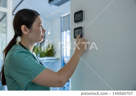 Dark-haired female doctor in lab coat setting the temperature range in a room Dark-haired female doctor in lab coat setting the temperature range in a room 140880707