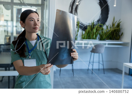 Long-haired asian female doctor with xray results in hands Long-haired asian female doctor with xray results in hands 140880752