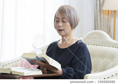 一位老婦人坐在沙發上,用智慧型手機學習英語會話。 一位老婦人坐在沙發上,用智慧型手機學習英語會話。 140880980