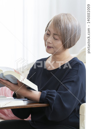 一位老婦人坐在沙發上,用智慧型手機學習英語會話。 一位老婦人坐在沙發上,用智慧型手機學習英語會話。 140881009