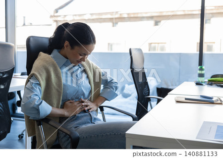 Woman with stomach pain leaning forward Woman with stomach pain leaning forward 140881133