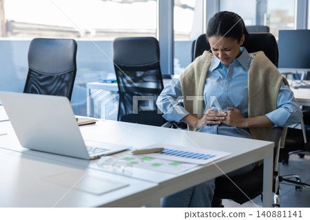 Woman feeling abdominal pain in office Woman feeling abdominal pain in office 140881141