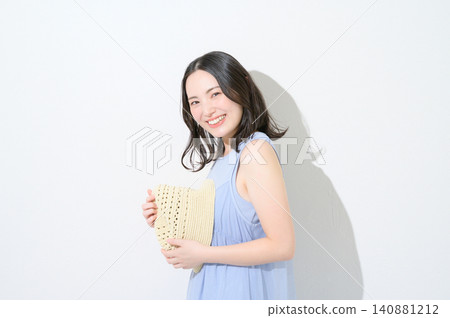 一位日本女性手持帽子,在白色背景前,展現出美麗的形象。 一位日本女性手持帽子,在白色背景前,展現出美麗的形象。 140881212
