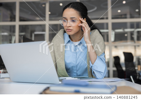 Stressed woman touching temple looking at laptop Stressed woman touching temple looking at laptop 140881245