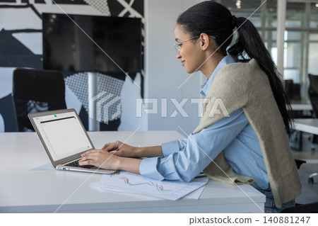 Profile of woman typing on laptop with charts Profile of woman typing on laptop with charts 140881247