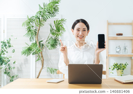 一位中年女性面帶微笑，手持智慧型手機。應用程式、社群媒體、推薦、評論、優惠券、積分、DX、搜尋、影片。 140881406