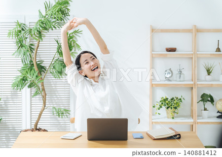 一位中年女性在工作之餘放鬆身心。休息、伸展、微笑、舒適、自由工作、在家工作、成就感滿滿。 一位中年女性在工作之餘放鬆身心。休息、伸展、微笑、舒適、自由工作、在家工作、成就感滿滿。 140881412