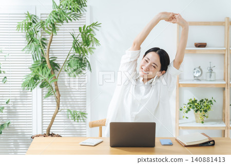 一位中年女性在工作之餘放鬆身心。休息、伸展、微笑、舒適、自由工作、在家工作、成就感滿滿。 一位中年女性在工作之餘放鬆身心。休息、伸展、微笑、舒適、自由工作、在家工作、成就感滿滿。 140881413