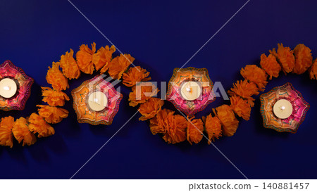 Festive Diwali border with lit clay diyas and marigold flower garland on blue background Festive Diwali border with lit clay diyas and marigold flower garland on blue background 140881457