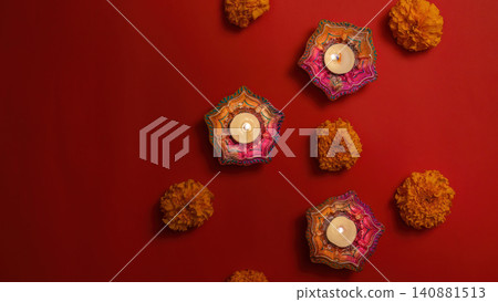 Diwali decoration with burning clay diyas and marigold flowers on red background Diwali decoration with burning clay diyas and marigold flowers on red background 140881513