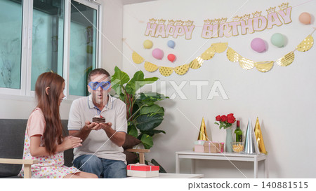Funny Caucasian father with heart glasses blowing birthday cake candle with daughter Funny Caucasian father with heart glasses blowing birthday cake candle with daughter 140881515