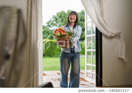 Asian woman carrying basket of fresh flowers into her new home Asian woman carrying basket of fresh flowers into her new home 140881557