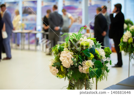 Floral arrangement highlights vibrant atmosphere at social event in modern venue during daytime gathering Floral arrangement highlights vibrant atmosphere at social event in modern venue during daytime gathering 140881646