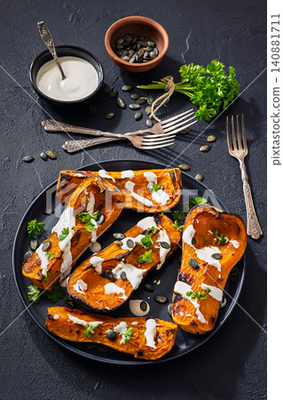 Baked butternut squash halves with yogurt sauce 140881711