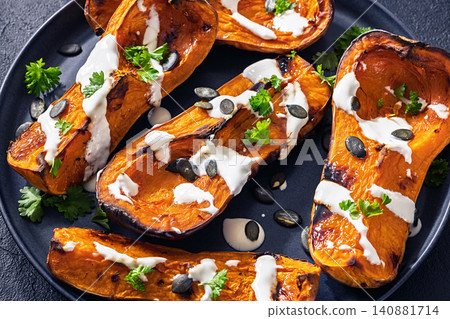 Baked butternut squash halves with yogurt sauce 140881714