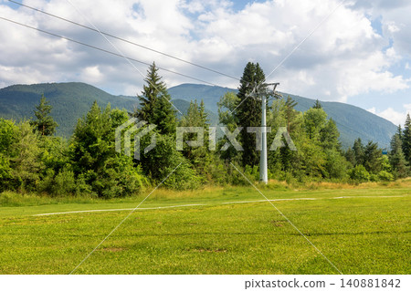 Bansko, Bulgaria summer landscape of Pirin mountains with lush green forests and a ski lift tower on a grassy meadow Bansko, Bulgaria summer landscape of Pirin mountains with lush green forests and a ski lift tower on a grassy meadow 140881842
