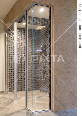 glass shower room, dark mosaic tile interior and a geometric wooden wall pattern in a luxury spa glass shower room, dark mosaic tile interior and a geometric wooden wall pattern in a luxury spa 140881845