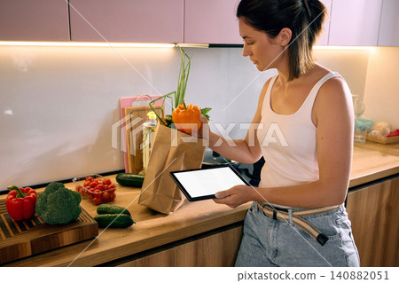 Woman packing fresh vegetables from grocery delivery at home Woman packing fresh vegetables from grocery delivery at home 140882051