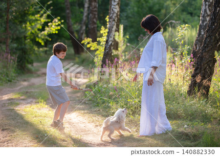 The family enjoys a playful day in a sunny forest with a dog and a child engaged in carefree fun. The family enjoys a playful day in a sunny forest with a dog and a child engaged in carefree fun. 140882330