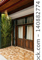 serene wooden door with glass panels and metal bars on outdoor porch area, traditional home decor setting, clean and bright interior design, brown and green natural materials. 140882774