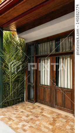 serene wooden door with glass panels and metal bars on outdoor porch area, traditional home decor setting, clean and bright interior design, brown and green natural materials. serene wooden door with glass panels and metal bars on outdoor porch area, traditional home decor setting, clean and bright interior design, brown and green natural materials. 140882774