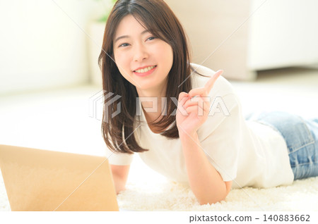 一名日本女子坐在地板上使用筆記型電腦,並指著某些東西。 一名日本女子坐在地板上使用筆記型電腦,並指著某些東西。 140883662