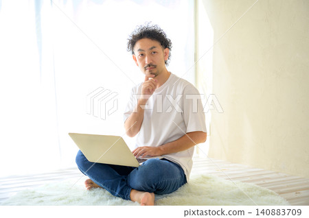 一位日本男子在家用筆記型電腦思考。 一位日本男子在家用筆記型電腦思考。 140883709