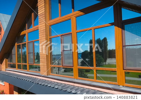 House with a gray metal roof and large windows on the facade. Corrugated metal roof and metal roofing. Modern roof made of metal. 140883821