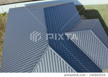 House with a gray metal roof. Corrugated metal roof and metal roofing. Modern roof made of metal. House with a gray metal roof. Corrugated metal roof and metal roofing. Modern roof made of metal. 140883839