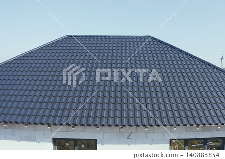 House with a gray metal roof. Corrugated metal roof and metal roofing. Modern roof made of metal. House with a gray metal roof. Corrugated metal roof and metal roofing. Modern roof made of metal. 140883854