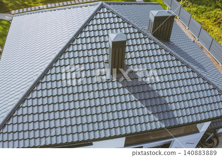 House with a gray metal roof. Corrugated metal roof and metal roofing. Modern roof made of metal. House with a gray metal roof. Corrugated metal roof and metal roofing. Modern roof made of metal. 140883889