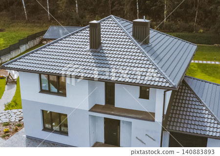 House with a gray metal roof. Corrugated metal roof and metal roofing. Modern roof made of metal. House with a gray metal roof. Corrugated metal roof and metal roofing. Modern roof made of metal. 140883893