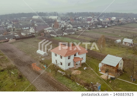 New houses under construction in the village. Houses with a roof made of metal. Corrugated metal roof and metal roofing. Modern roof made of metal. New houses under construction in the village. Houses with a roof made of metal. Corrugated metal roof and metal roofing. Modern roof made of metal. 140883925