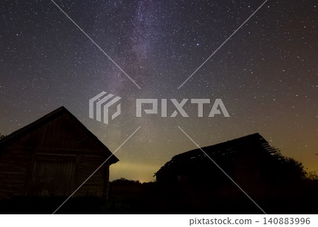 Starry sky over wooden houses in the village. Starry sky background picture of stars in night sky and the Milky Way. Starry sky over wooden houses in the village. Starry sky background picture of stars in night sky and the Milky Way. 140883996