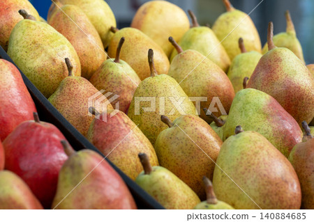 Pears on a food market or supermarket counter. A close-up of fresh, ripe, delicious pears, neatly arranged in a market display. Demonstration of organic vegetarian and healthy food. 140884685