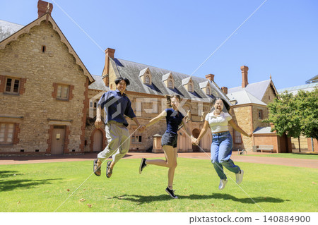 A group of international university students jumping in front of the university. A group of international university students jumping in front of the university. 140884900
