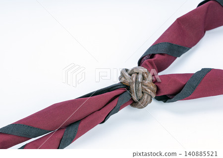 Traditional Thai boy scout uniform maroon and black neckerchief held together by a handcrafted brown leather Turk's head woggle knot displayed on a clean bright white studio background close up Traditional Thai boy scout uniform maroon and black neckerchief held together by a handcrafted brown leather Turk's head woggle knot displayed on a clean bright white studio background close up 140885521