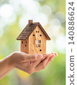 Hands holding a miniature model of a house against a blurred background 140886624