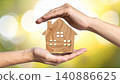 Hands holding a miniature model of a house against a blurred background 140886625