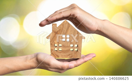 Hands holding a miniature model of a house against a blurred background 140886625