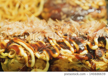 Okonomiyaki grilled on a hot plate with sauce and mayonnaise Okonomiyaki grilled on a hot plate with sauce and mayonnaise 140886639