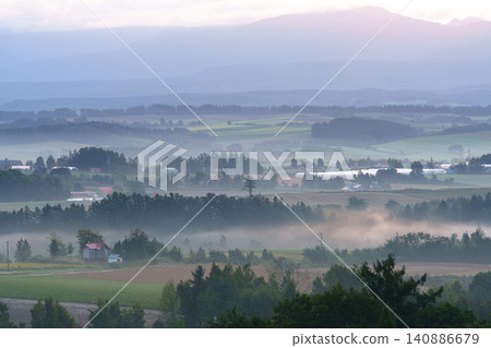 北海道美瑛市的秋日清晨:起伏的丘陵籠罩在晨霧之中,構成了一幅如夢似幻的鄉村景色。 北海道美瑛市的秋日清晨:起伏的丘陵籠罩在晨霧之中,構成了一幅如夢似幻的鄉村景色。 140886679