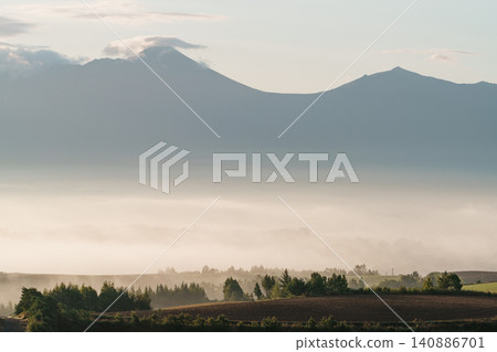 北海道美瑛和富良野的清晨:十勝山脈和綿延的丘陵籠罩在晨霧之中。 北海道美瑛和富良野的清晨:十勝山脈和綿延的丘陵籠罩在晨霧之中。 140886701